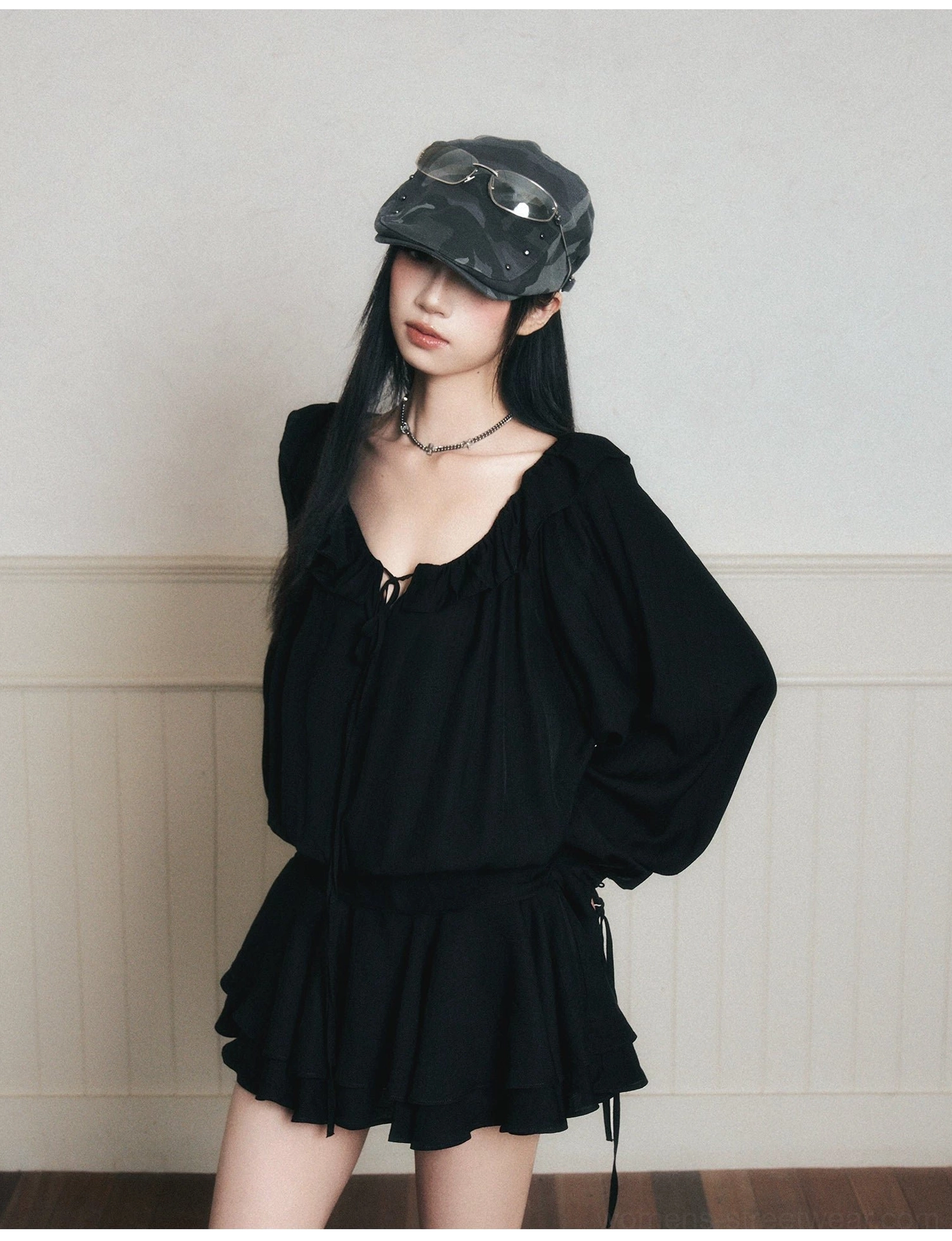 Close-up of black ruffle poet mini dress showing adjustable ruched V-neck tie, flared cuffs and tiered skirt details