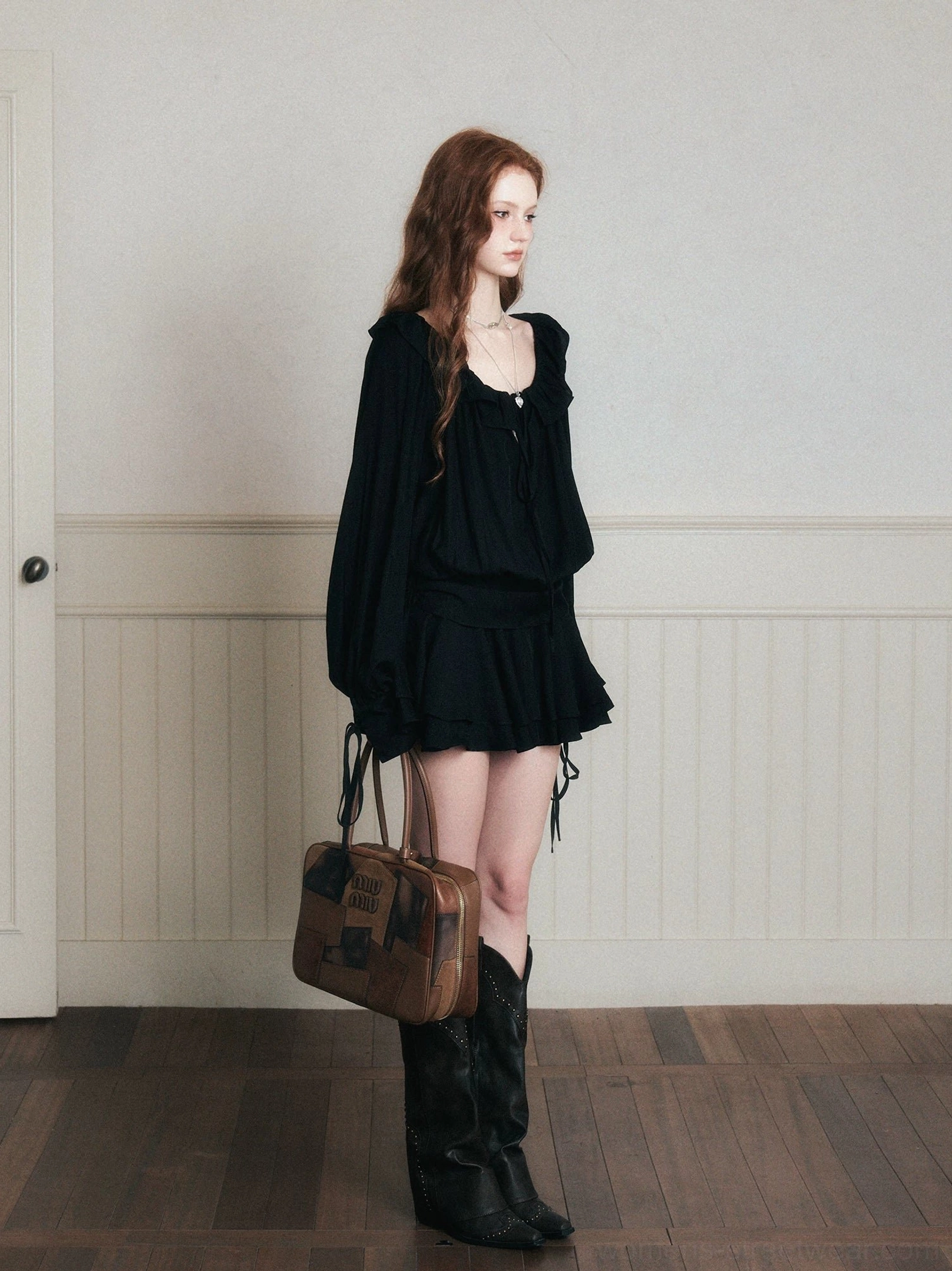 Right side view of black poet mini dress set showing adjustable side drawstrings, ruffled hem and tie-front neckline