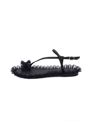 Black ruffle-trim bow strappy flat sandals shown from a top-down view with open toe, adjustable ankle buckle, and romantic streetwear detailing