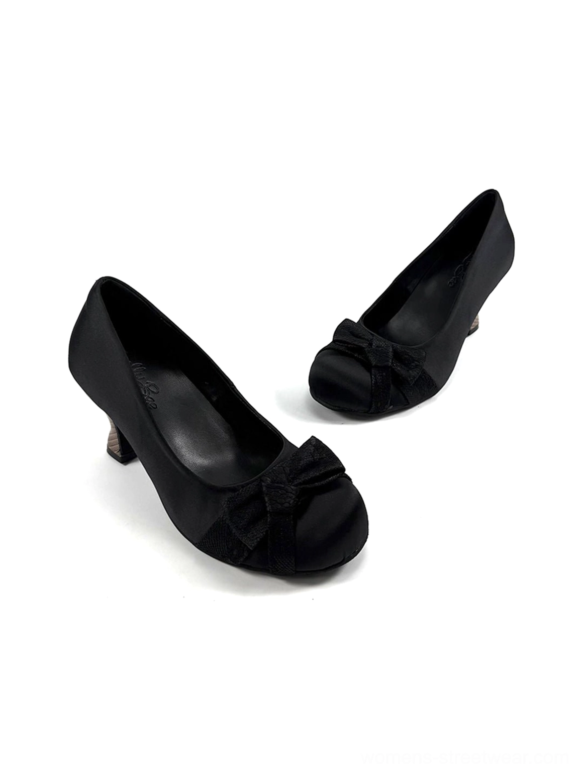 Black satin bow pumps in a low angled product view showing the side sole, gathered bow, and sculpted cup heel