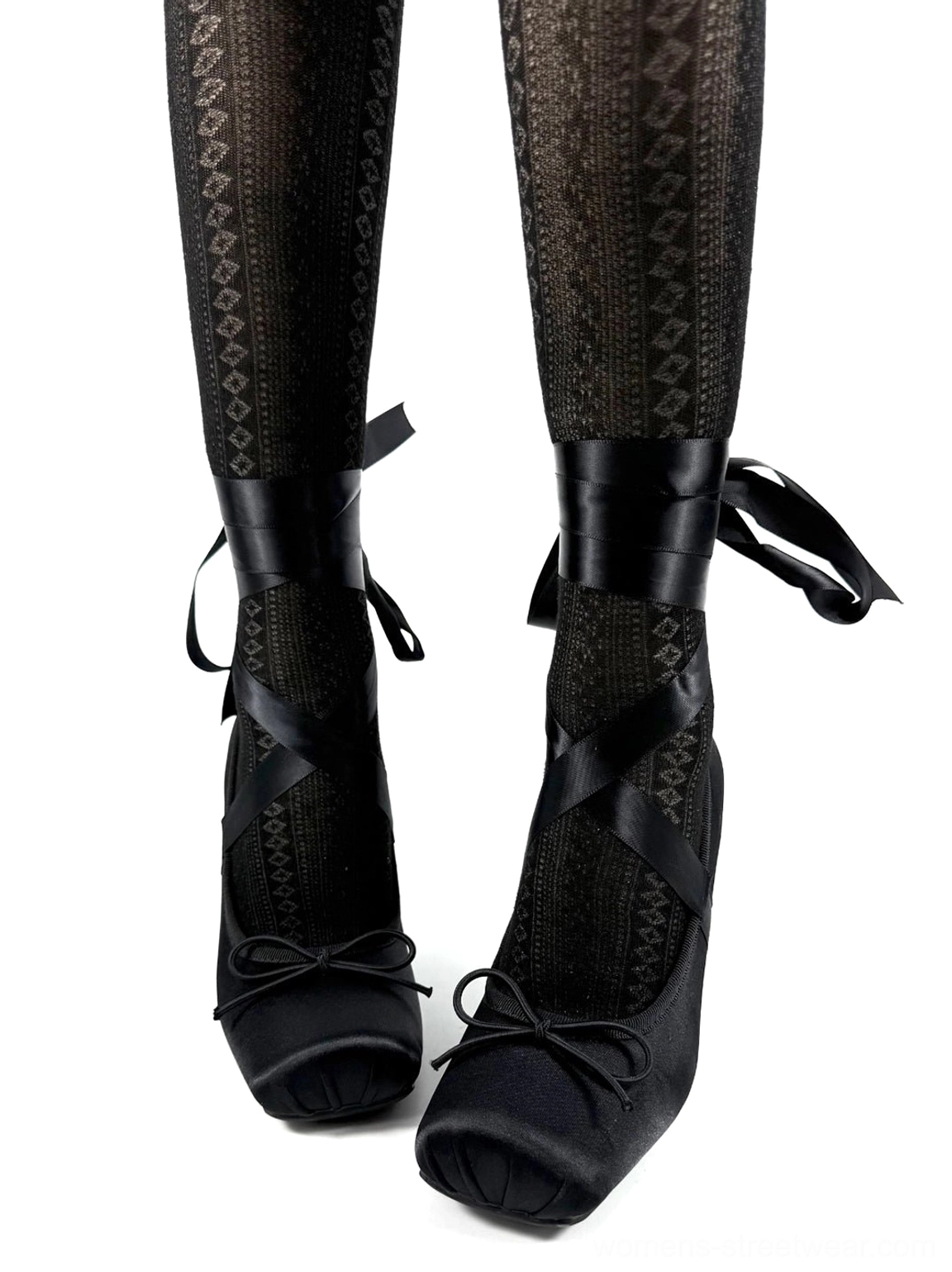 Black satin bow strap pumps worn with patterned sheer tights, showing the square toe, ankle ribbons, and heart buckle detail