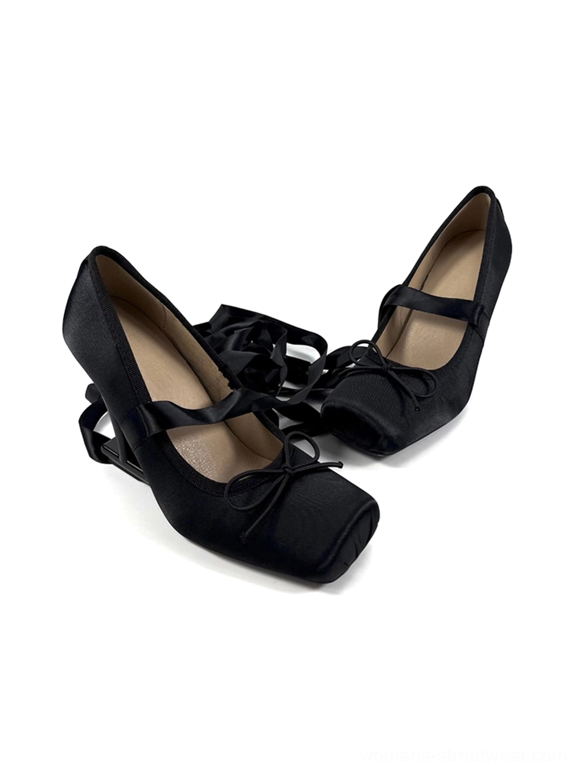 Top angled view of black satin square toe pumps with front bow decorations, ribbon ankle straps, and metal buckles
