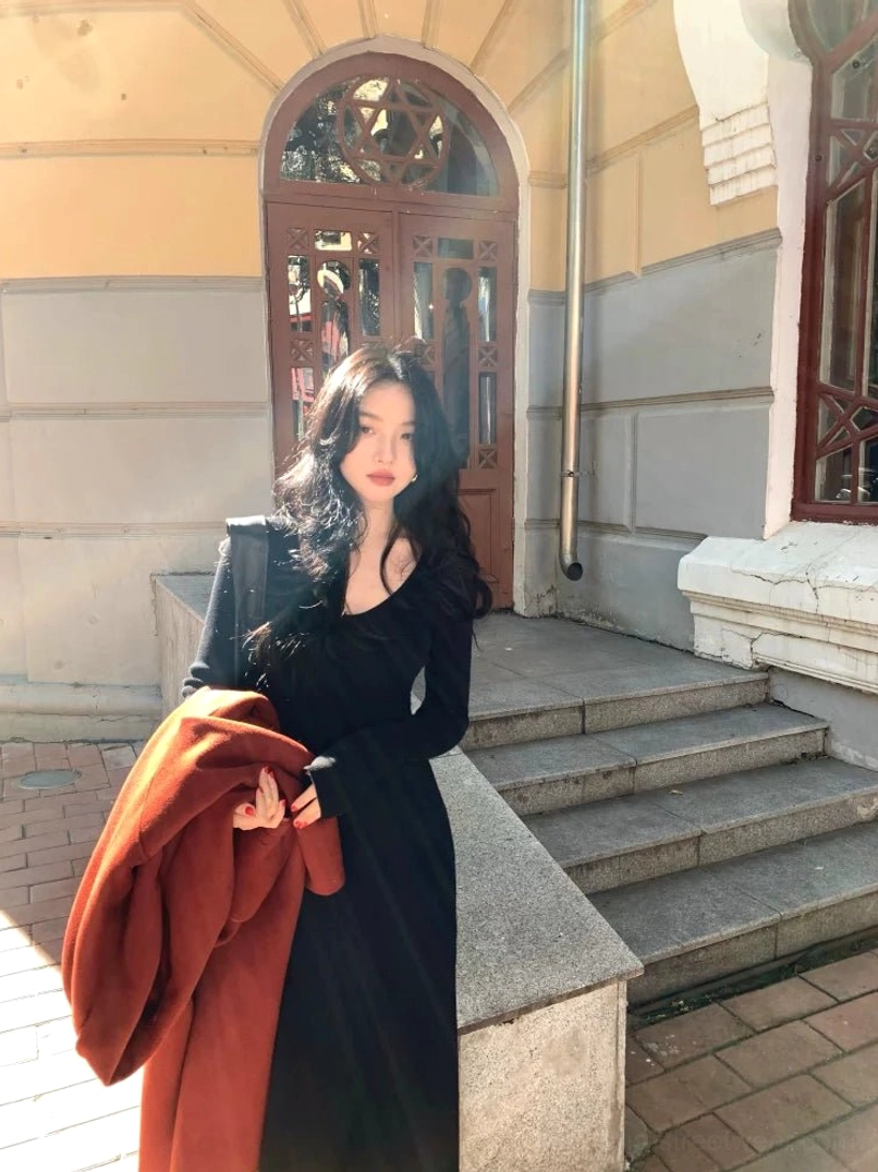 Black long sleeve scoop neck fitted knit maxi dress styled on outdoor vintage building steps with a floor-length hem