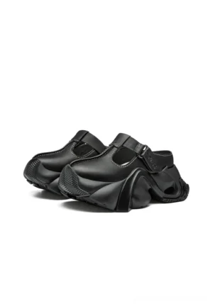 Black sculpted closed-toe platform slides in paired side view with adjustable T-strap buckle and hollowed chunky outsole
