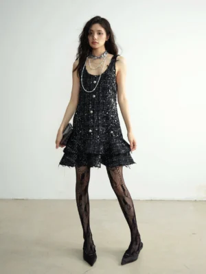 Full front view of a black sequin tweed mini dress with scoop neckline, decorative front buttons, and frayed tiered ruffle hem