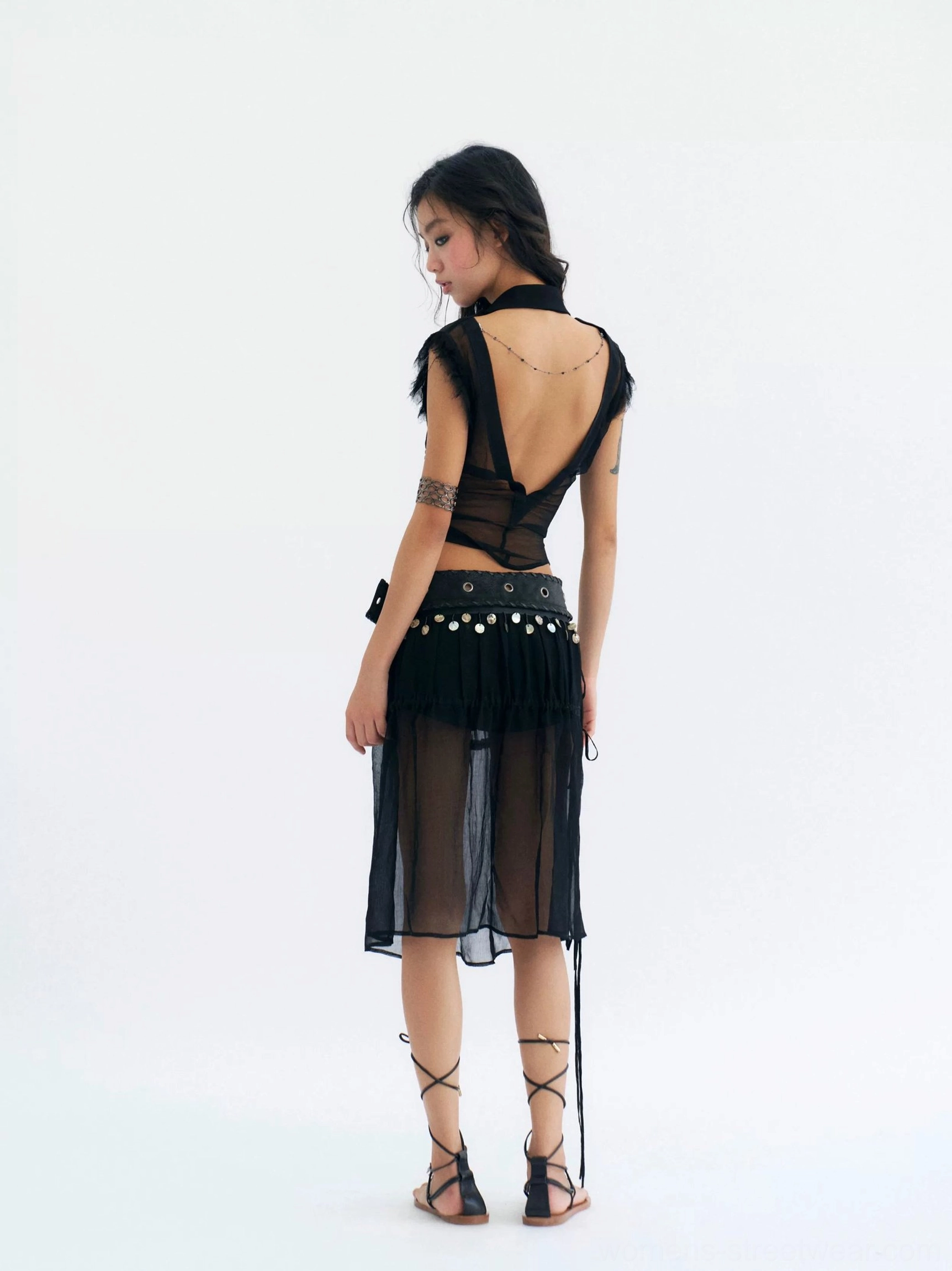 Rear full body view of black sheer coin belt midi skirt with transparent rayon overlay