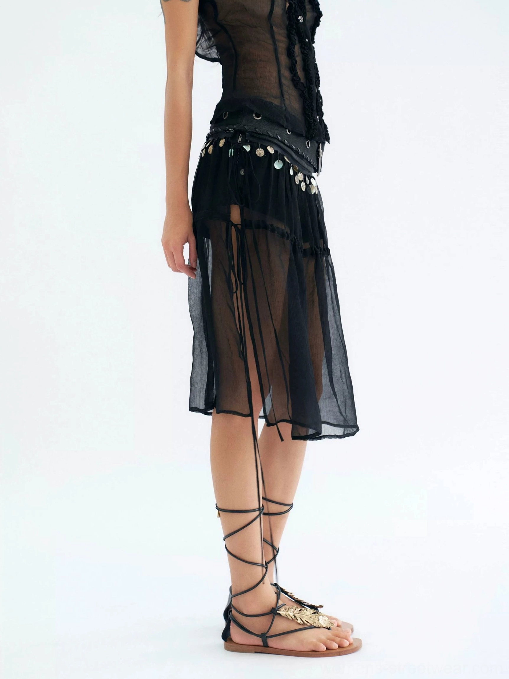 Side view of black sheer coin trim midi skirt with adjustable drawstrings and gladiator sandals