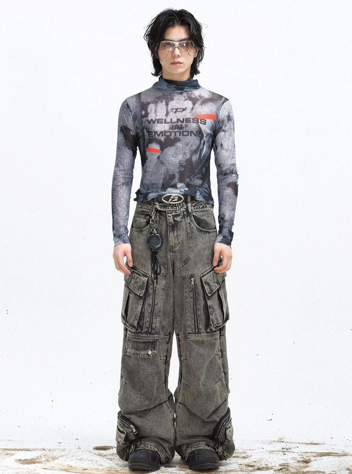Black sheer mesh long-sleeve turtleneck streetwear top styled with gray washed cargo jeans and layered metal accessories