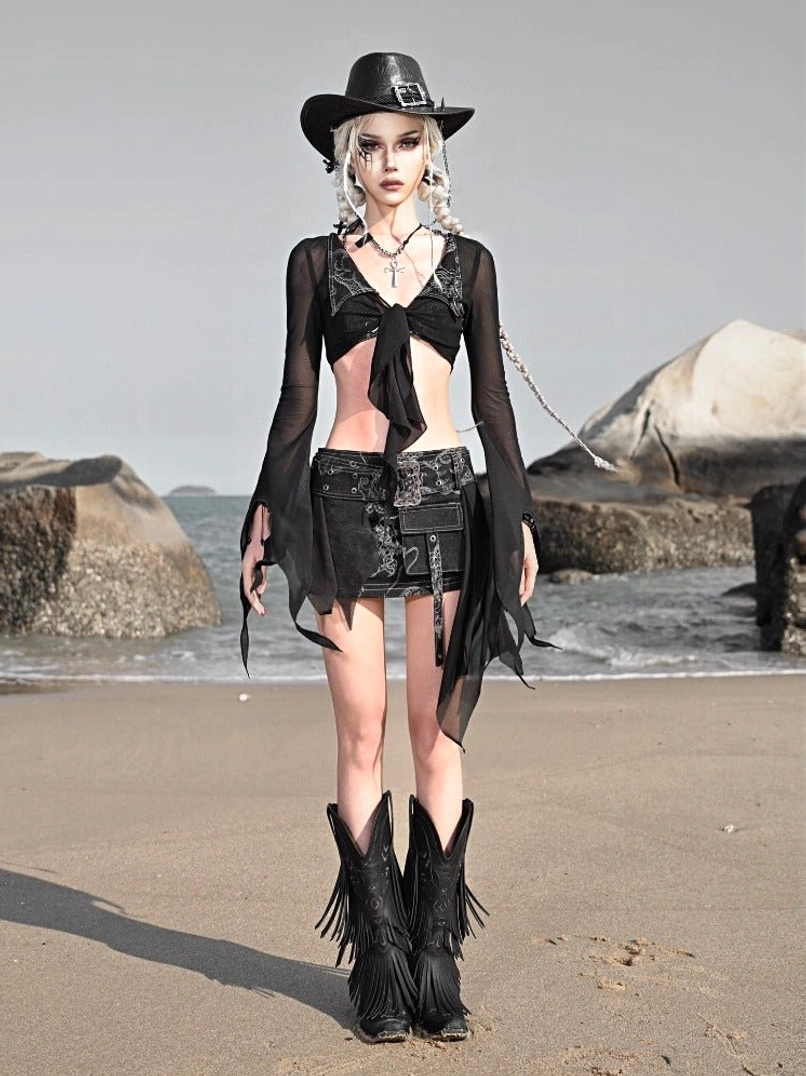 Black sheer mesh short cardigan with dramatic flare sleeves styled in a gothic western festival outfit on a rocky beach