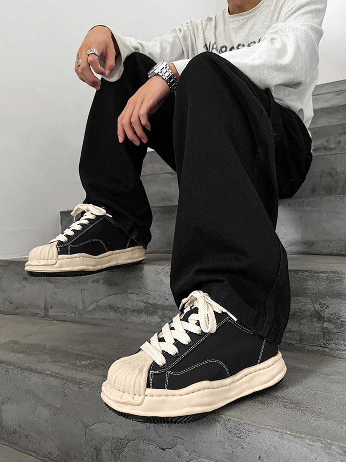 Black shell-toe court sneakers with aged cream overlays and exaggerated platform sole for Y2K streetwear outfits