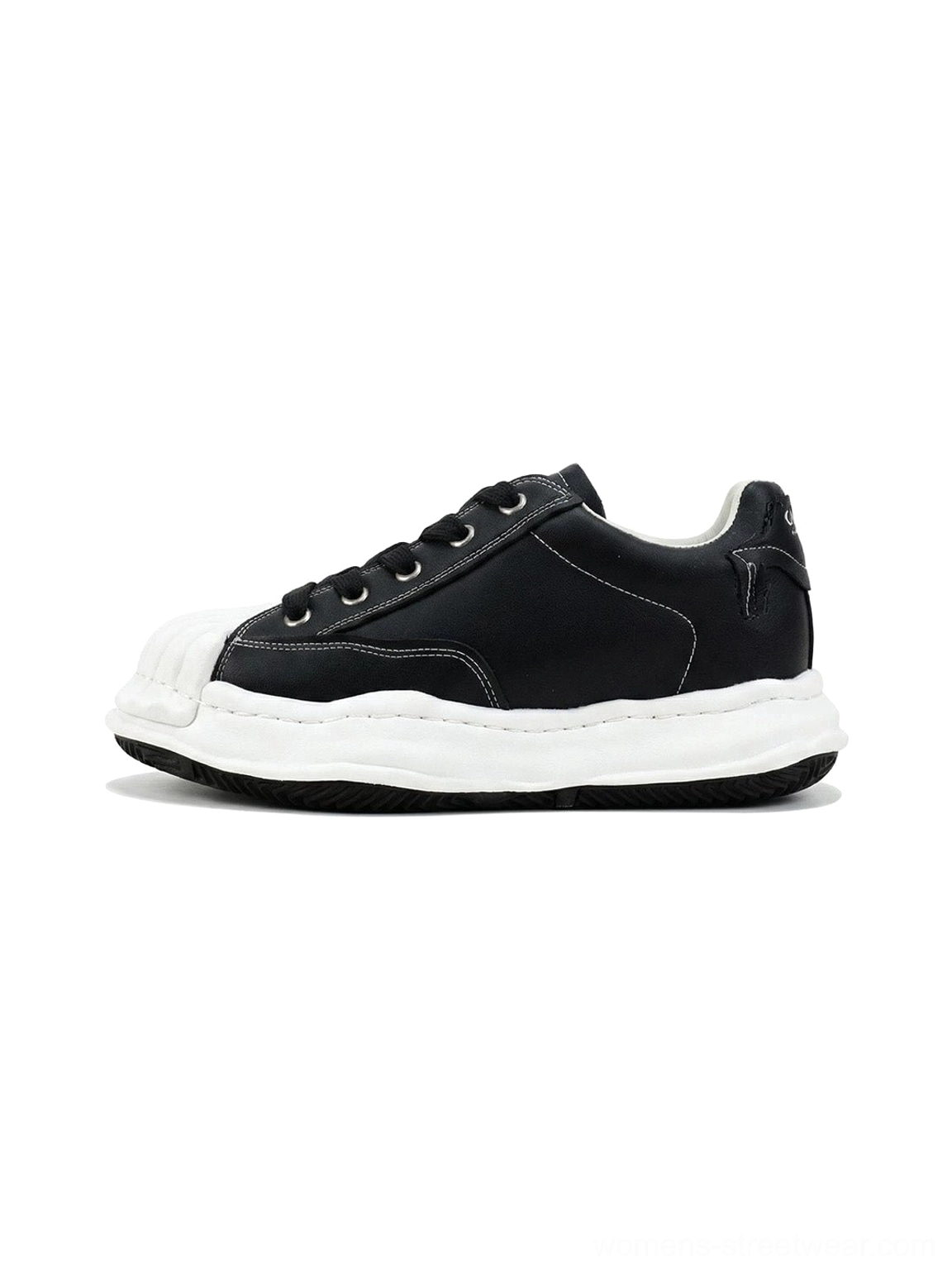 Black shell-toe court sneakers in a side frontal product view with matte synthetic-leather upper, molded white toe cap, thick white sole, and black lace-up design
