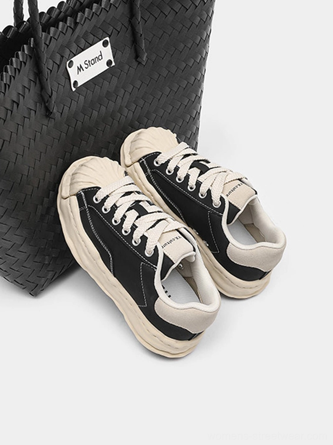 Black shell-toe platform sneakers close-up showcasing the lace-up upper, rounded toe, and bold Y2K streetwear profile