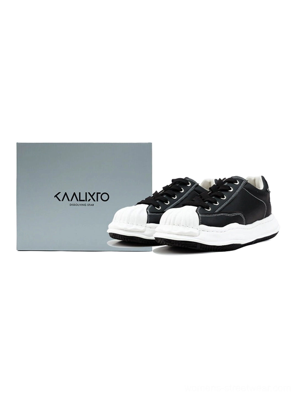Black shell-toe sneakers displayed beside neutral packaging in a clean studio flat-lay product presentation