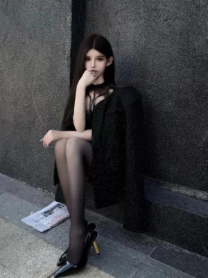 Black shimmer collarless structured cropped jacket draped over shoulder in dark editorial streetwear styling