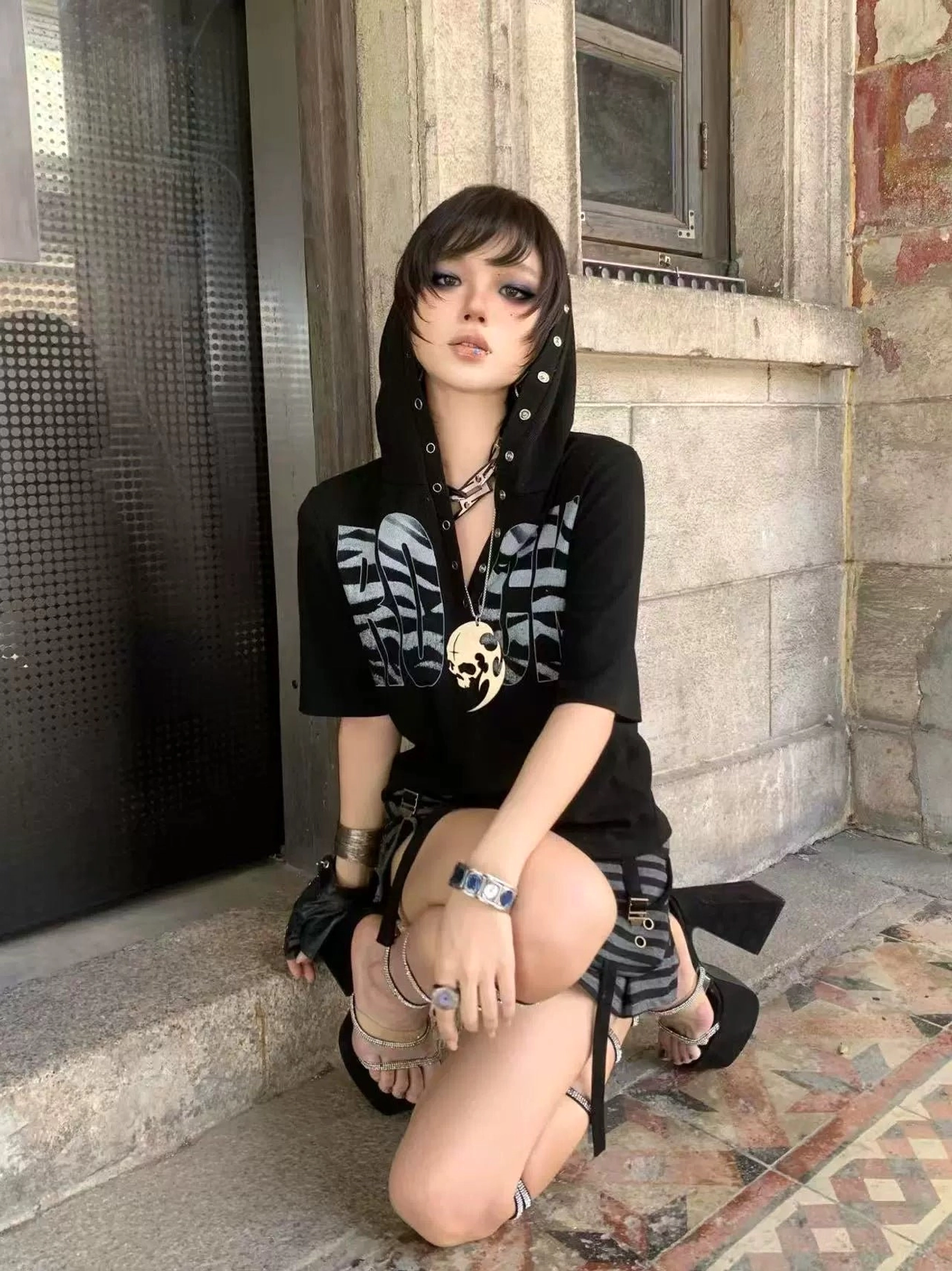 Black short-sleeve hooded graphic T-shirt with silver wing chest print and grommet details styled outdoors