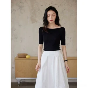 Black silk lyocell boat neck half sleeve fitted knit top styled with a white midi skirt in a minimalist studio front view