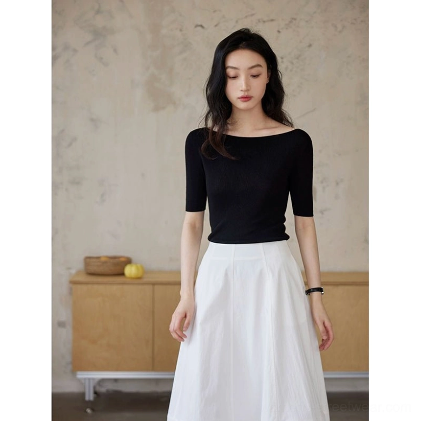 Black silk lyocell boat neck half sleeve fitted knit top styled with a white midi skirt in a minimalist studio front view