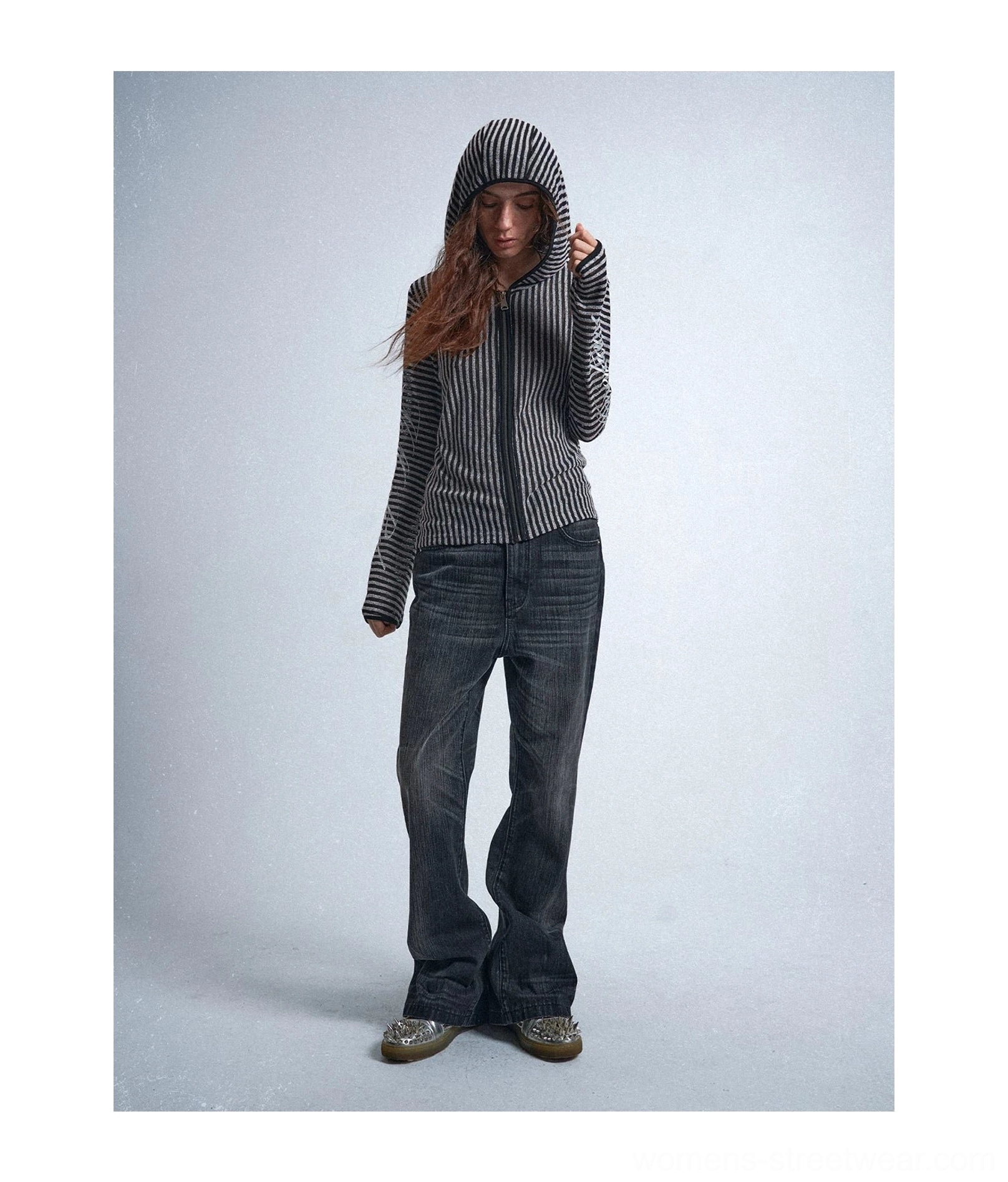 Full-body front view of a black and silver striped hooded zip-up shirt styled with dark denim and chunky loafers