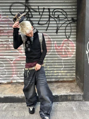 Black skull stripe collar long sleeve polo sweatshirt styled on a blonde male model in punk streetwear accessories during an outdoor street fashion shoot