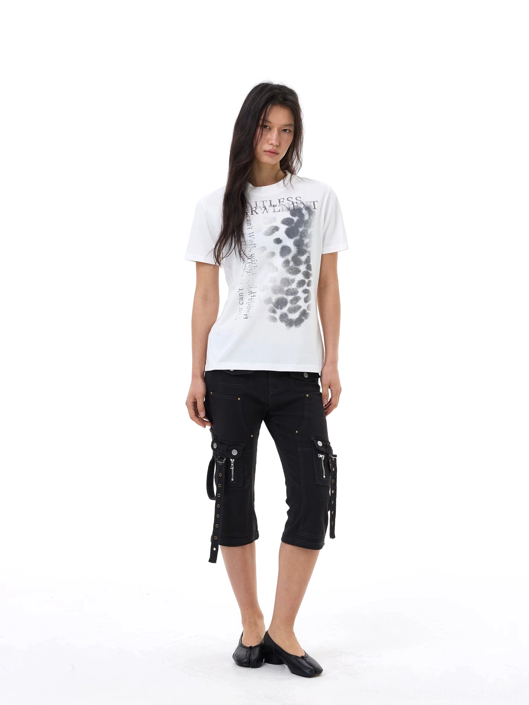 Front full-body streetwear outfit featuring black slim cargo capri jeans, a printed white graphic T-shirt, black flats, and functional side pockets