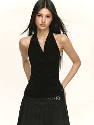 Black slim fit draped cowl neck halter top styled with a black pleated skirt and belt hardware for a Y2K streetwear outfit