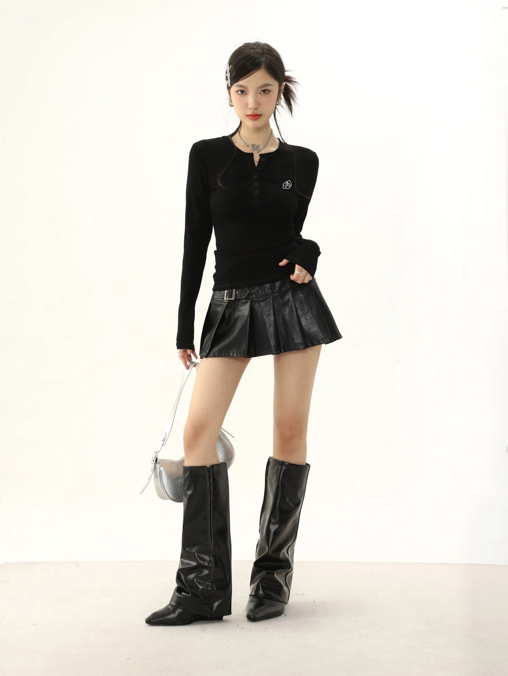 Black slim-fit ribbed half-button collar long-sleeve streetwear top styled with a pleated leather mini skirt and knee-high boots