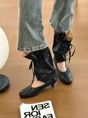 Black slouch leather sandal boots styled with cropped straight-leg blue jeans in a modern streetwear outfit