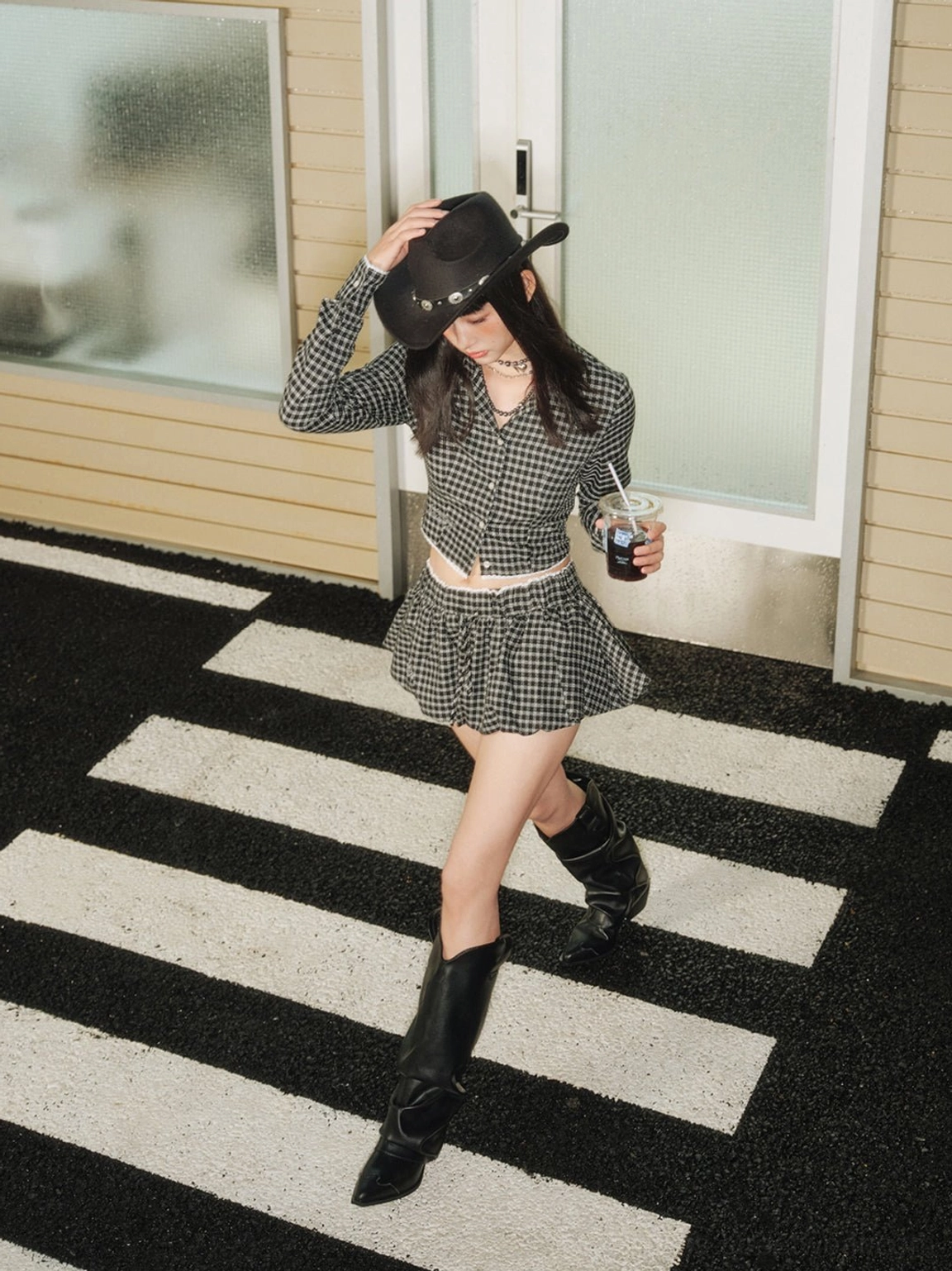 Side walking view of a female model in black slouched cowboy boots with relaxed knee-high shaft and low heel