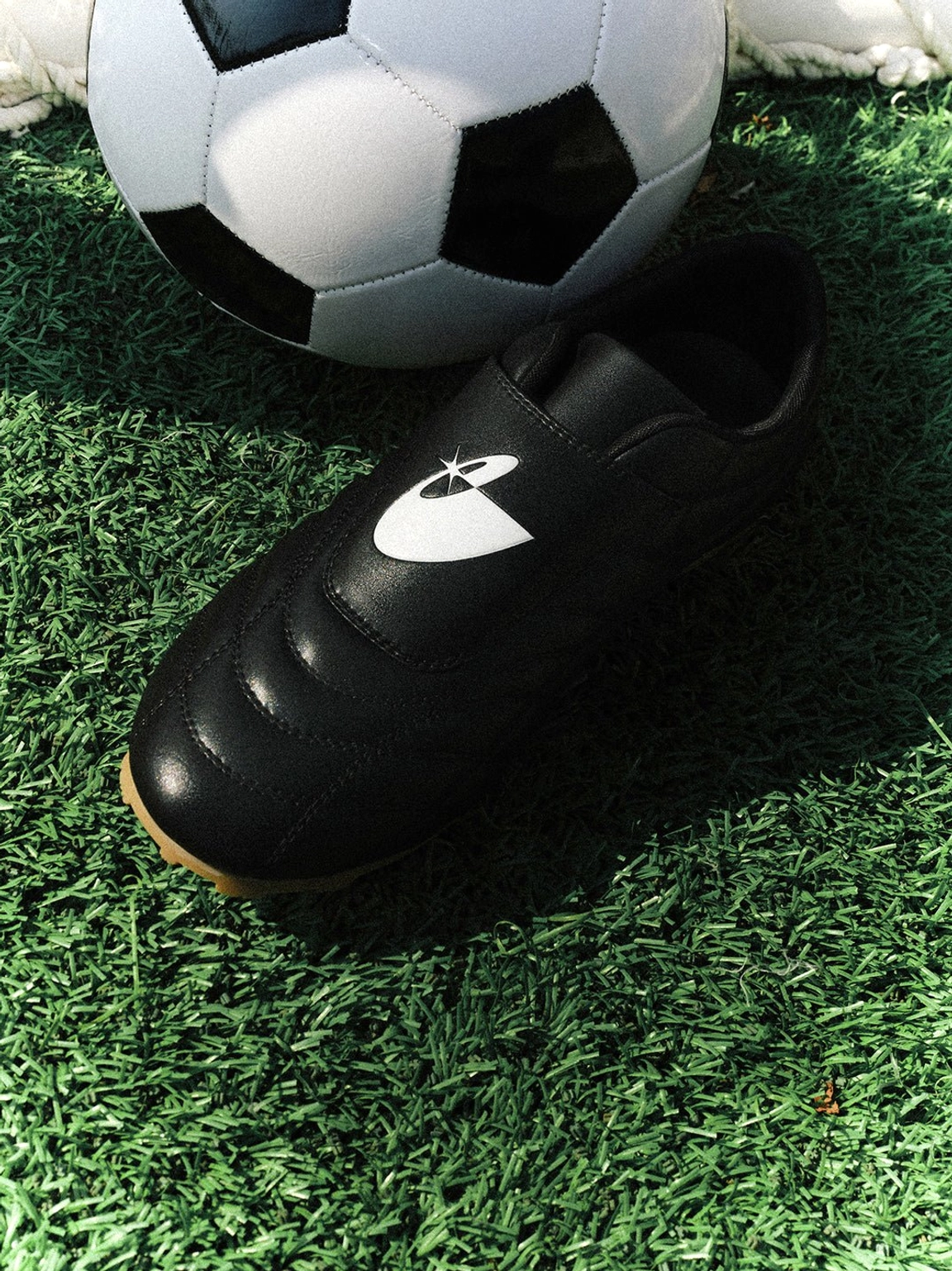 Black soccer-inspired streetwear sneakers with textured quilted upper and retro gum rubber sole