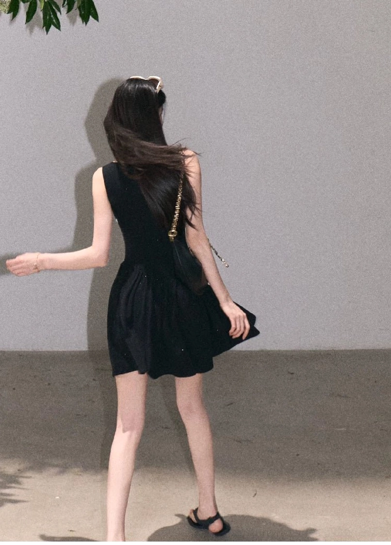 Back view of black sparkly asymmetrical lace waist mini dress with sleeveless silhouette and flared skirt