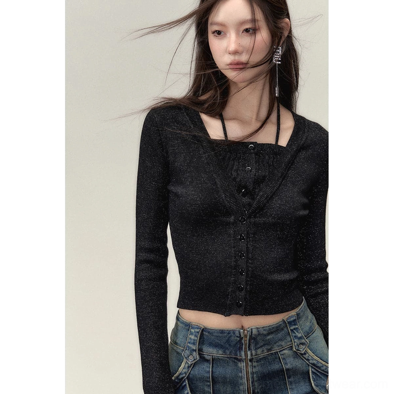 Woman styling a black sparkly faux two-piece knit crop top with low-rise baggy blue jeans and long drop earrings in Korean streetwear fashion
