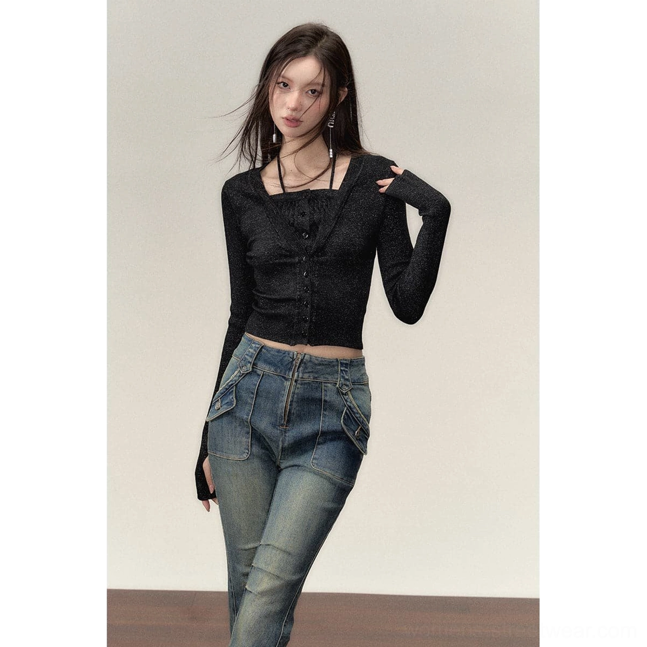 Front styling view of a black sparkly halter-effect faux two-piece cropped knit top worn with relaxed low-rise jeans and statement earrings