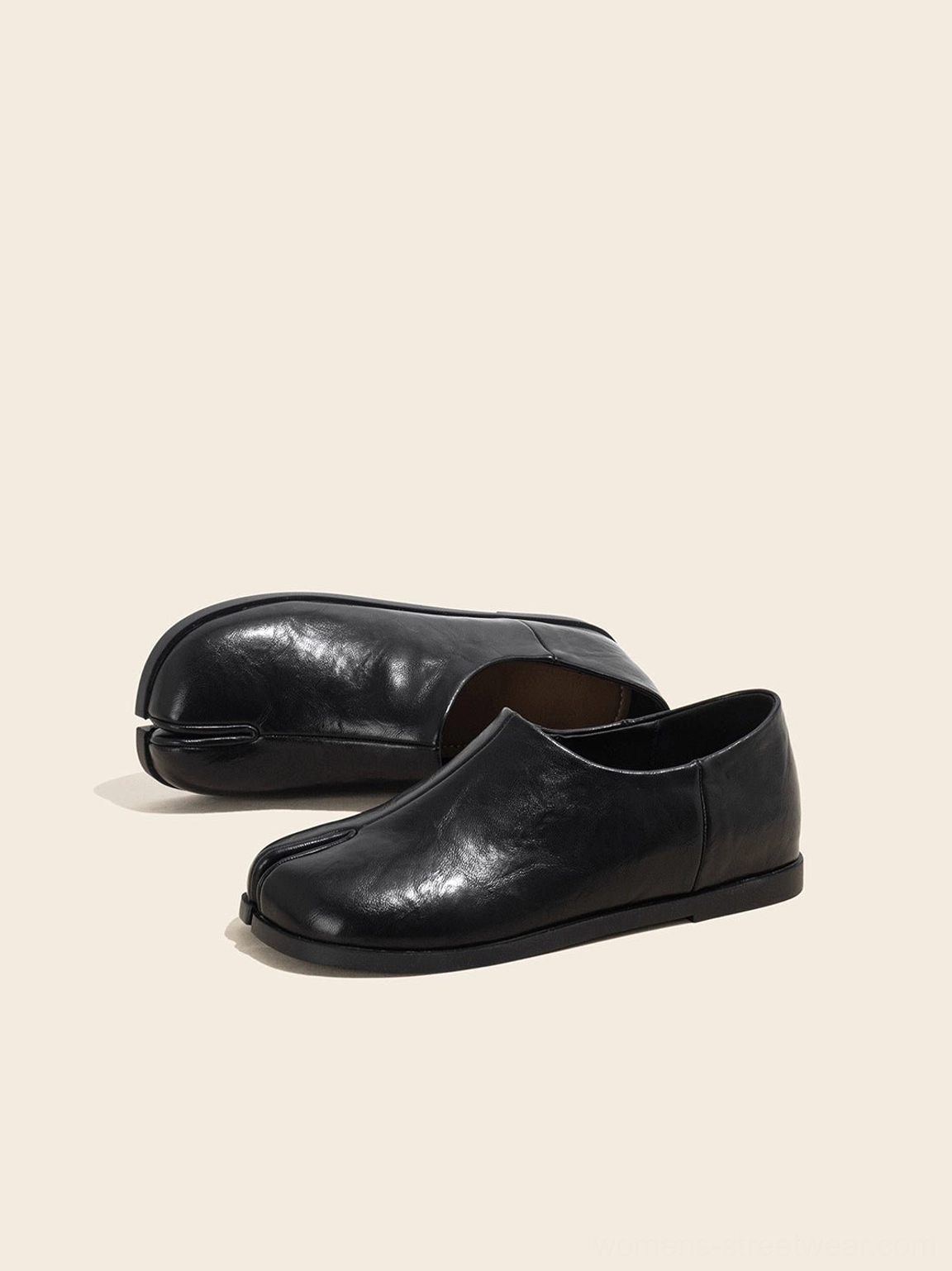 Right front three-quarter view of black split-toe leather loafers showing both the side profile and softly squared toe