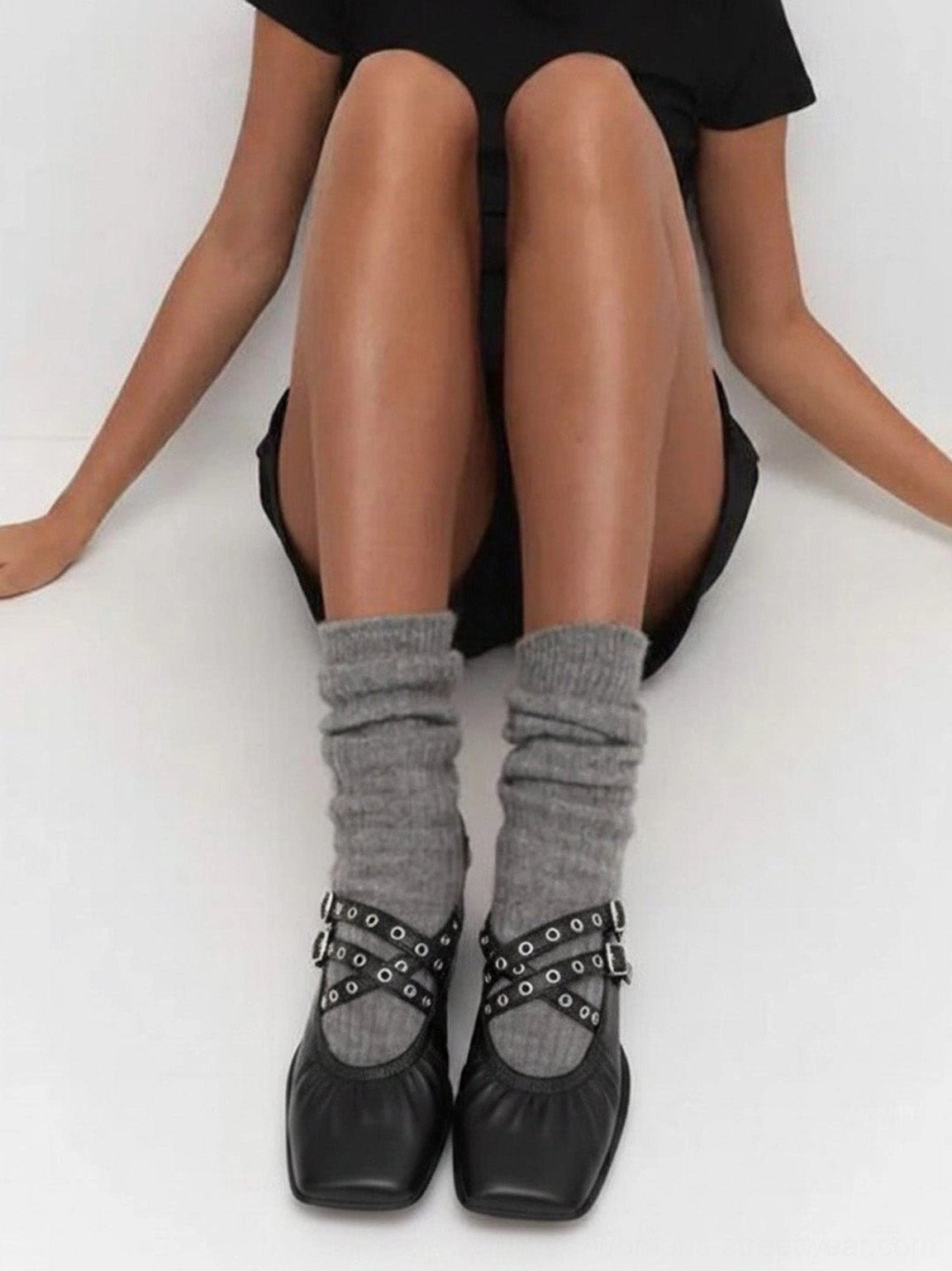 Black square-toe Mary Jane flats with silver grommet double straps worn with gray crew socks