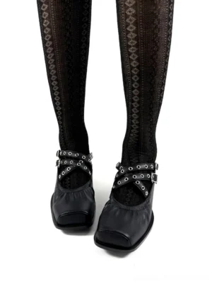 Black square-toe double-strap Mary Jane flats worn with patterned sheer tights in a front close-up streetwear styling view
