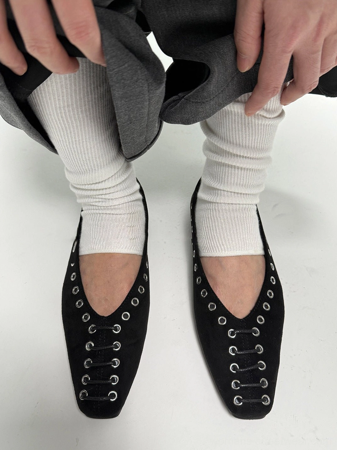 Top view of black square-toe ballet flats with silver eyelet hardware styled in a Korean streetwear outfit