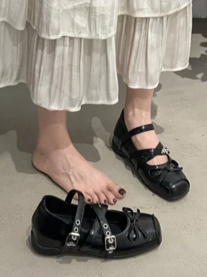 Black leather square-toe Mary Jane flat styled with a white pleated midi skirt in a streetwear outfit