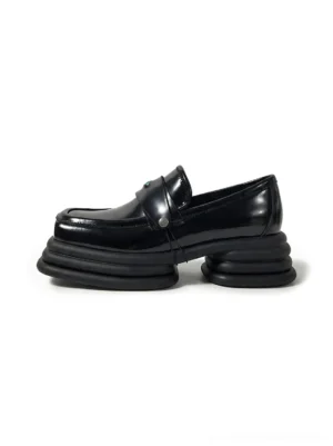 Black glossy square-toe platform loafers with detachable metal hardware strap and layered split sole shown from a left three-quarter angle