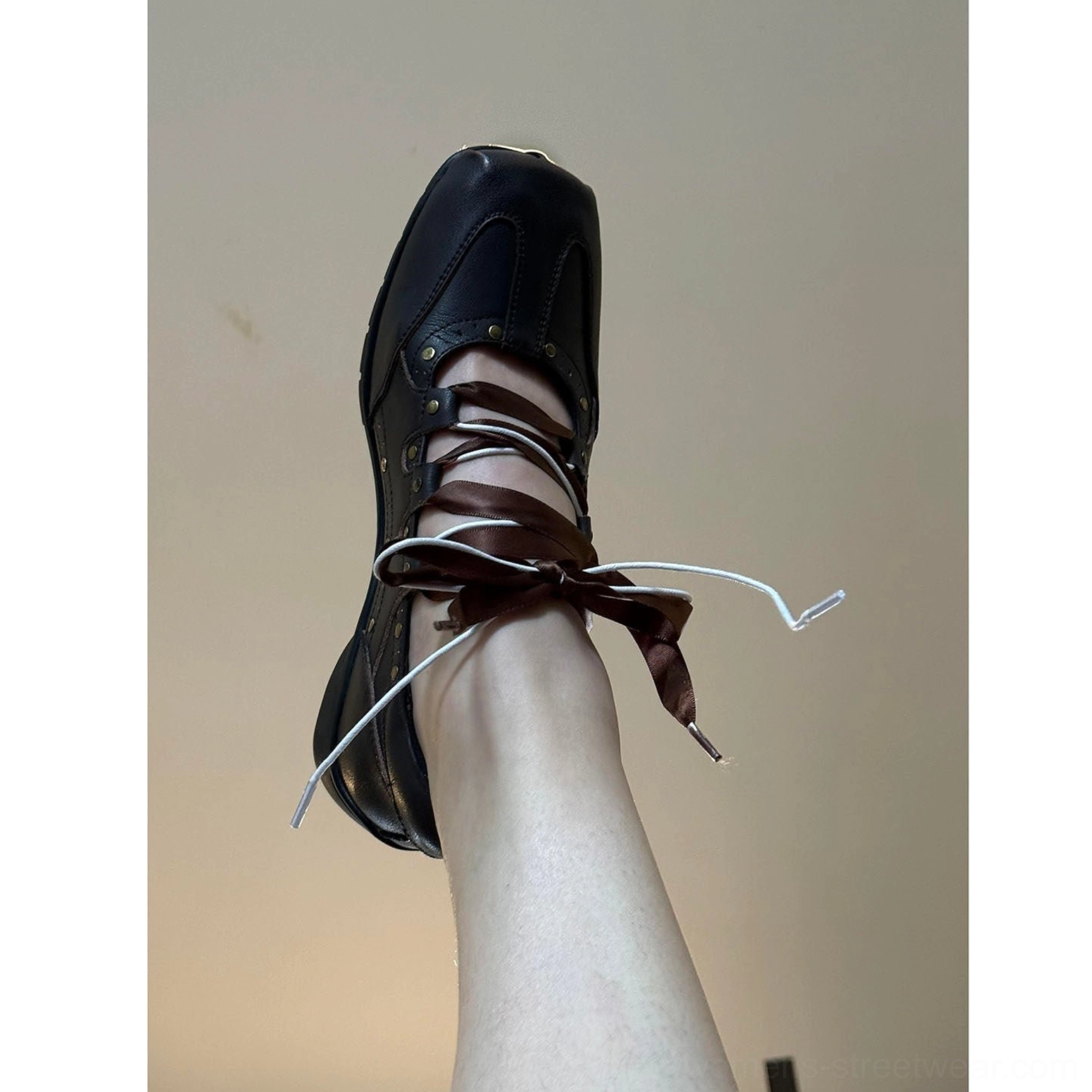 Close-up of black square toe ballet trainer sneaker with tied satin ribbon bow and decorative vamp studs