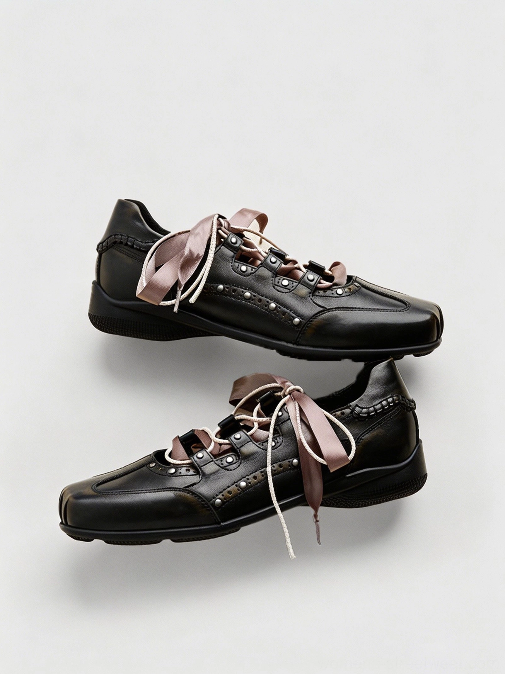 Top-down flat lay of a pair of black square toe satin ribbon lace-up ballet trainer sneakers with metal studs