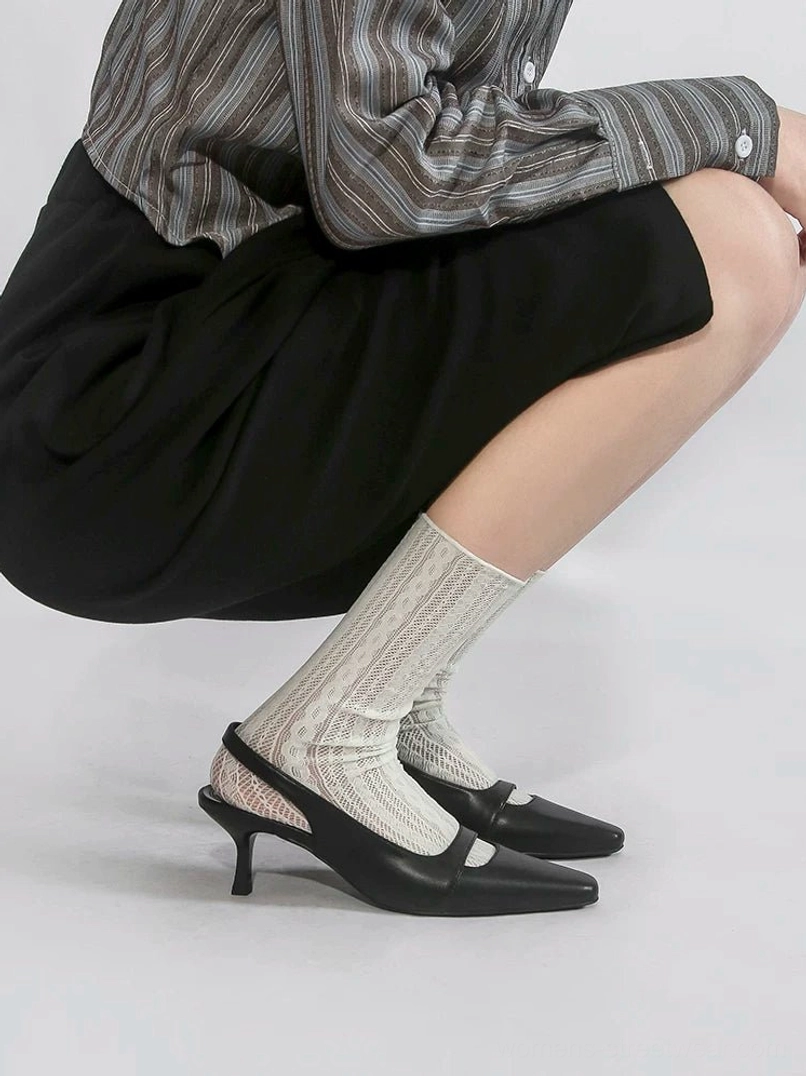 Black square-toe slingback heels shown in side profile with an open heel design, slim vamp strap, low kitten heel, striped shirt, and black midi skirt