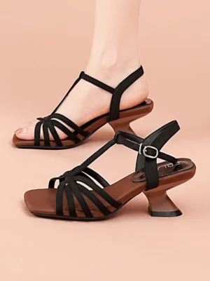 Black square-toe T-strap heeled sandal worn on a foot showing woven straps brown insole and metal ankle buckle