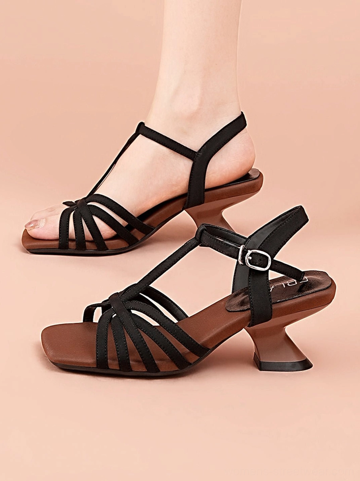 Black square-toe T-strap heeled sandal worn on a foot showing woven straps brown insole and metal ankle buckle