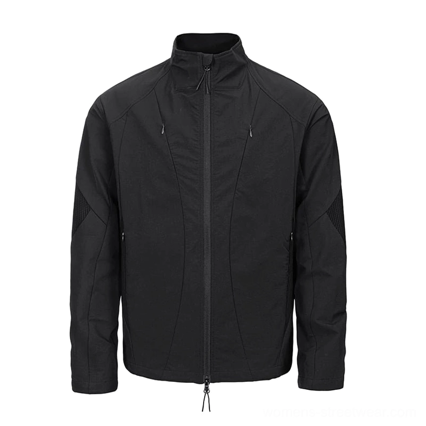 Black techwear stand-collar softshell jacket shown from the front with multiple zippered pockets, geometric panel stitching, reinforced elbow details, and adjustable hem