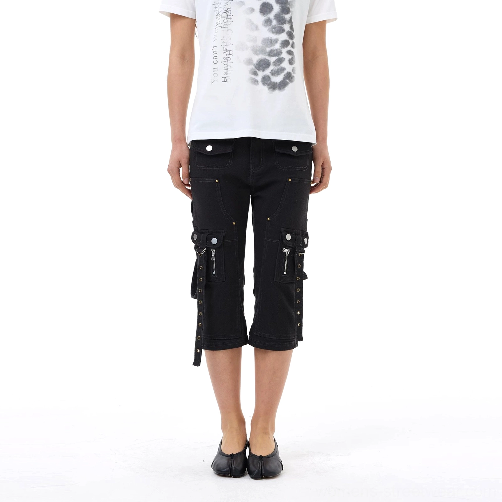 Black strap cargo capri jeans displayed on a white background, showing slim cropped silhouette, dual utility pockets, metal rivets, and hanging side straps