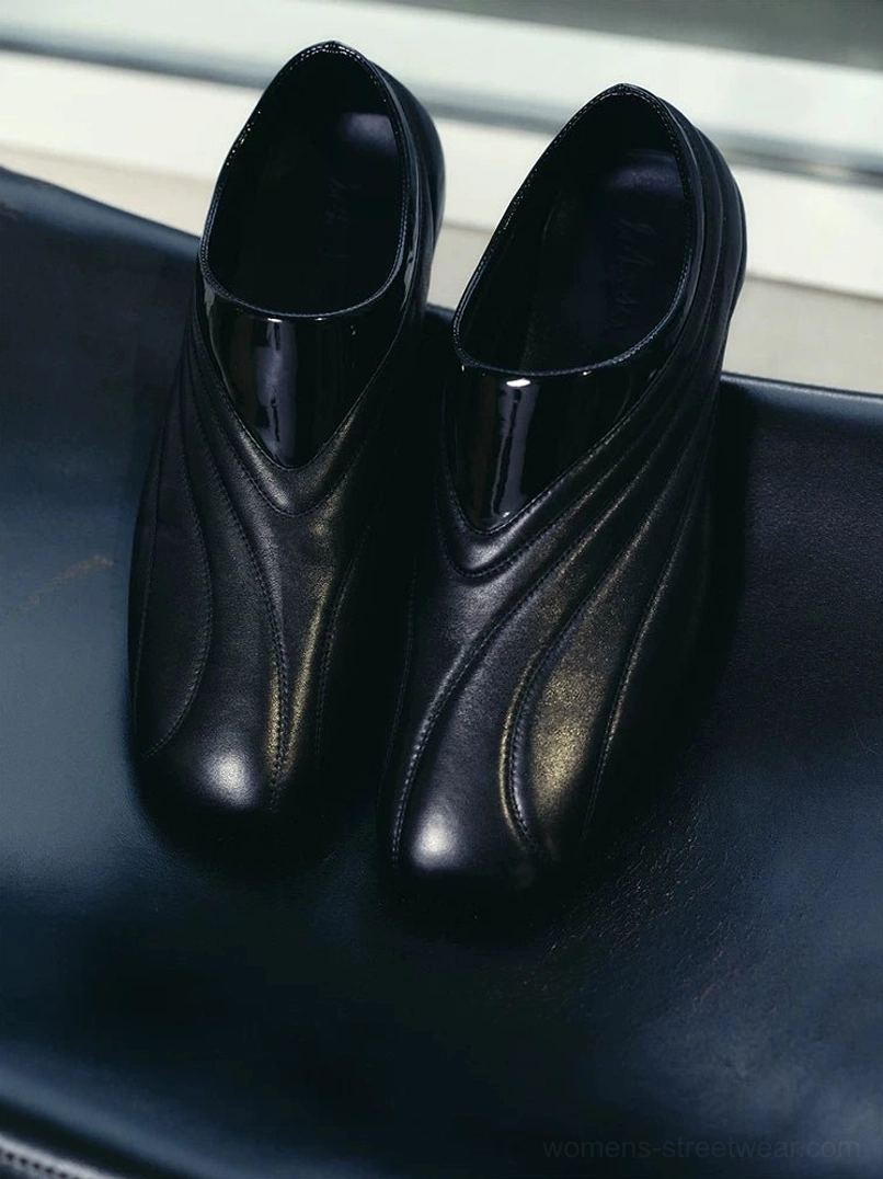 Top view of black streamlined leather slip-on shoes featuring wavy stitched uppers and patent-style collar detail