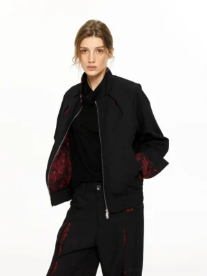 Model wearing a black streetwear bomber jacket with stand collar visible red floral lining and ribbed hem