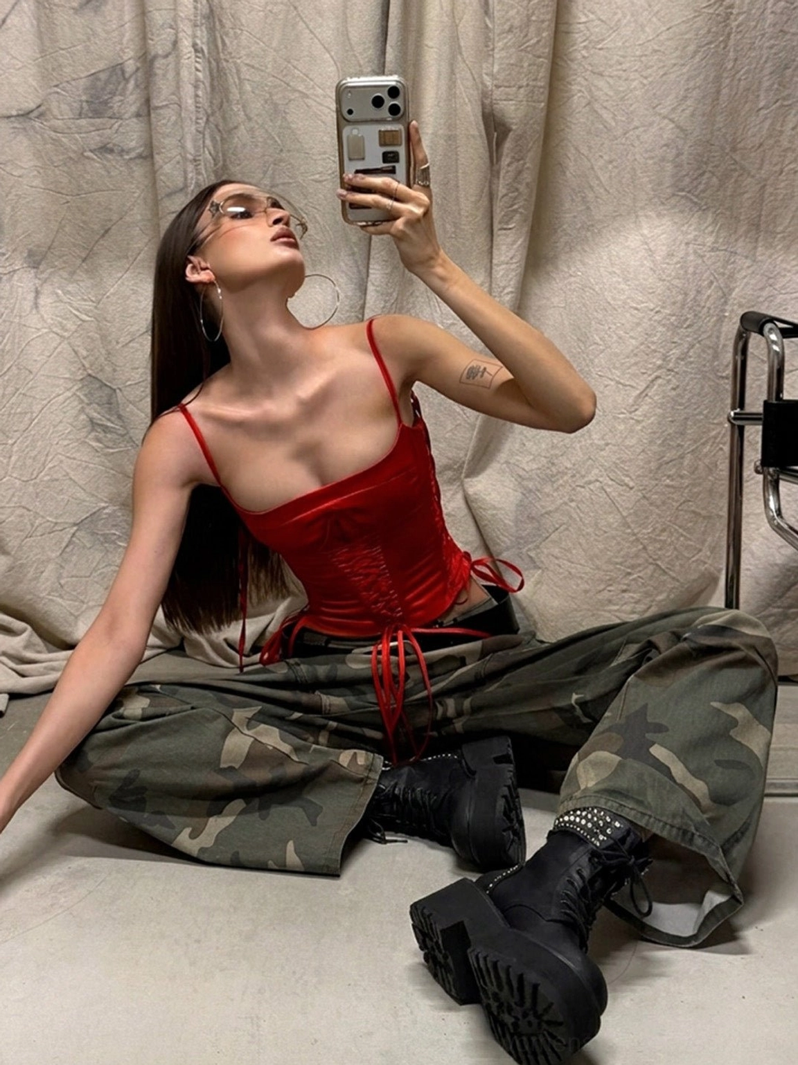 Black distressed leather combat boots with studded cuffs worn with camouflage cargo pants and a red corset top in an alternative Y2K outfit