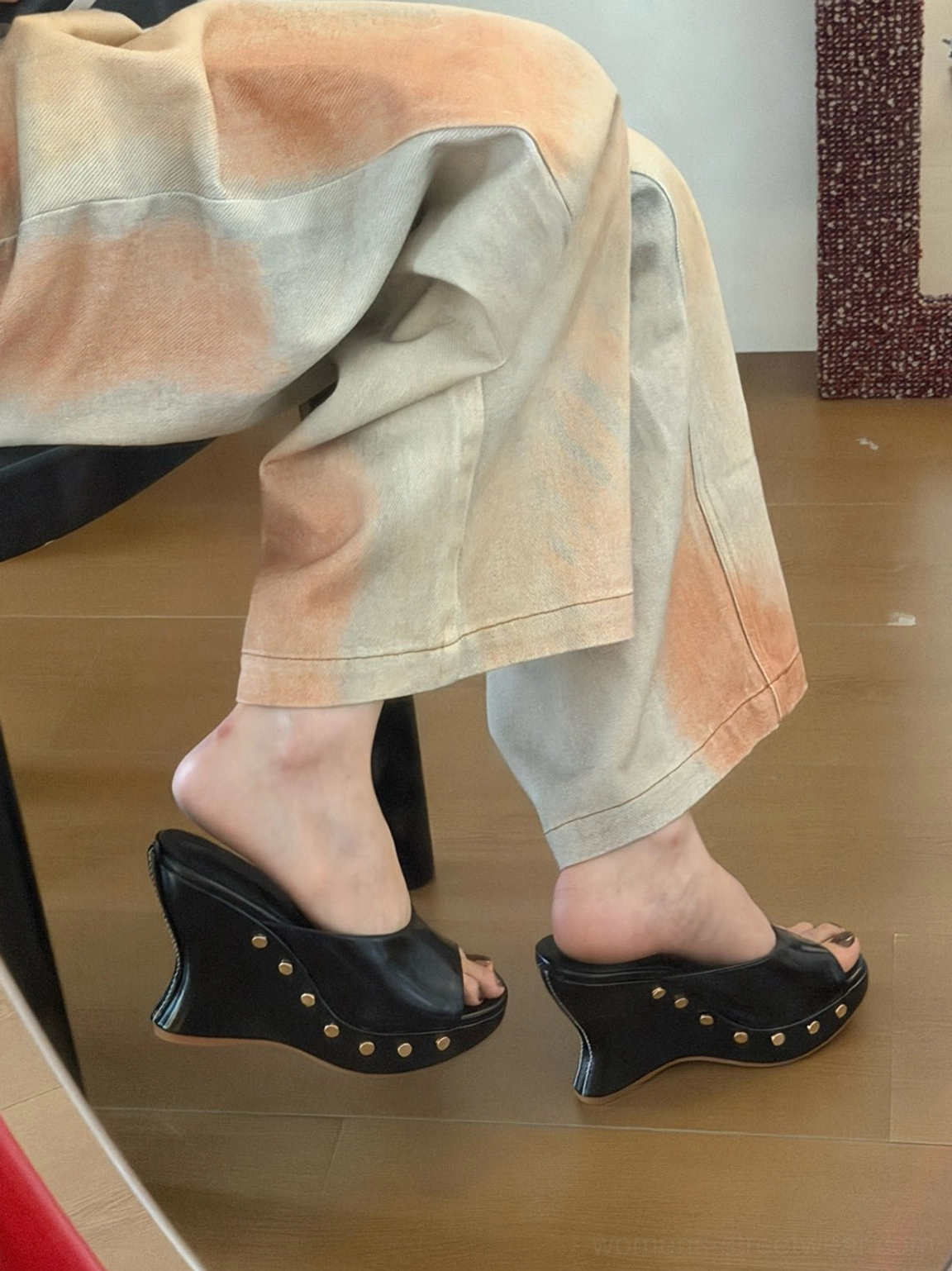 Both feet wearing black studded open-toe platform wedge mules in a non-mirror side view, displaying the full wedge profile and decorated sole edge