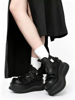 Female model wearing black studded platform ankle boots with white socks and a long black skirt in a streetwear outfit